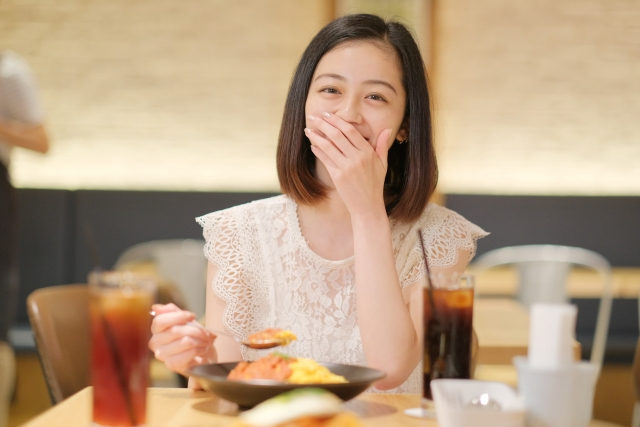 口元を覆って笑っている女性